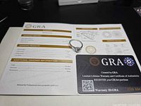 Ring placed on open GRA booklet alongside warranty card