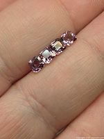 Four square cushion purple-pink spinels on fingertip