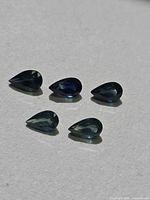 Five pear-cut sapphires arranged on neutral surface