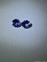 Two round violet-blue gemstones on light background