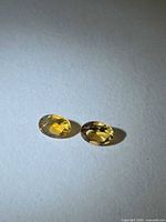Two oval golden citrine gemstones on neutral background