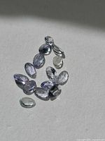 Group of oval cut light blue-purple Tanzanite gemstones on neutral background