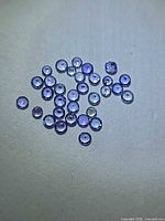 Cluster of small round deep blue Tanzanite stones on neutral background
