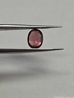 Oval pink champagne zircon held in tweezers profile view