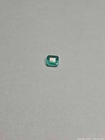 Emerald cut green gemstone on grey background