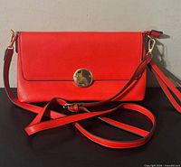 Front view showing red faux leather purse, flap and gold-tone turn-lock clasp, detachable strap