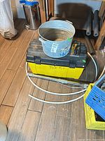 Toolbox labelled Tile Kit with bucket on top, clear hose, hand tools visible