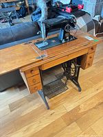 Full view of Singer treadle sewing machine in wood cabinet on cast iron base
