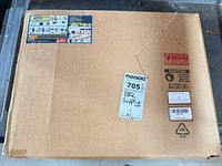 Sealed cardboard box containing cast iron grill grates with shipping labels