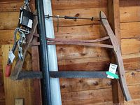 Full view of wood-frame crosscut saw hanging vertically, showing frame shape and full blade