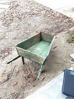 Full view of green wooden wheelbarrow