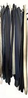 All 16 pairs of trousers hanging on rack showing variety of colours and fabrics
