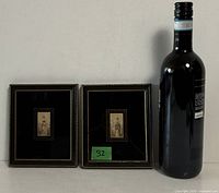 Both framed prints beside wine bottle for scale