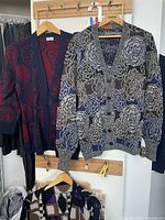 Two cardigans hanging: navy/red abstract and grey/blue floral, plus partial view of multicolour cardigan