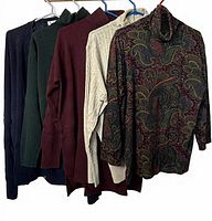Five sweaters on hangers showing colours and styles