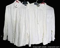 Four white blouses hanging side by side