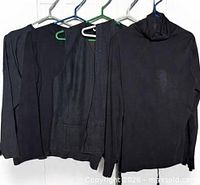 Four black tops and vest hanging