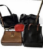 Five handbags: three black (shoulder, tote, tote with brown handles), one brown structured, one small red cross-body