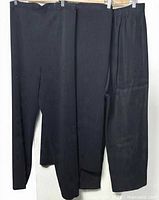 Three pairs of black trousers hanging side by side