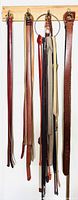 Belts hanging from wooden rack showing full length, colors, buckle styles and quantity