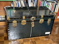 Closed black steamer trunk showing brass hardware and overall exterior condition