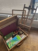 Paint box open showing contents and easel behind