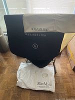 Black and beige Holt Renfrew garment bags and white Max Mara garment bag displayed