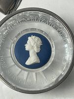 Top view of glass paperweight with blue-and-white queen cameo and engraved lettering
