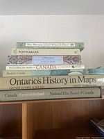 Stack of seven Canadian map books showing titles and authors