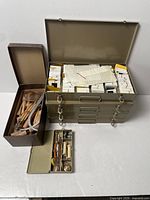 Stacked metal slide cases, woodgrain box of sculpting tools and open green compartment tool box