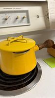Side view of yellow Dansk Kobenstyle saucepan with lid on stove