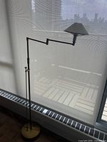 Full view of floor lamp showing articulating arm, shade, and brass base