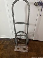 Front view of metal hand truck showing frame, toe plate with cutouts, overall wear