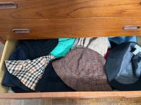 Open drawer showing multiple cloth hats in various colors and fabrics