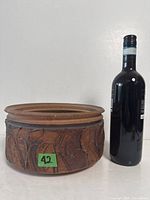 Full view of signed stoneware bowl beside wine bottle for scale