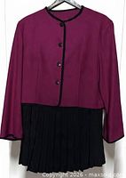 Front view of magenta blazer with black pleated skirt below