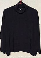 Full view of black turtleneck top hanging