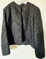 Full front view of black brocade jacket on hanger