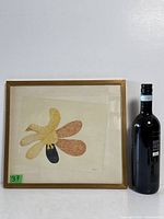 Framed drawing beside wine bottle for scale