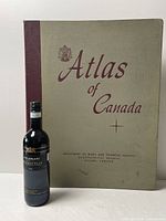 Front cover of 1957 Atlas of Canada with bottle for scale