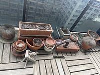 group of terracotta pots, rectangular planter, small pots, wooden stool on deck