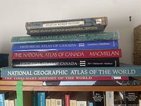 Stack of six atlas books showing spines and titles