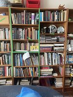 Front view of both mid-century modern wood bookshelves with staging items on shelves