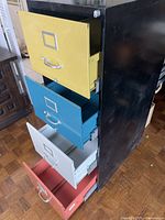 Cabinet with drawers open showing yellow, teal, light grey, red fronts and black case