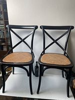 front view of two chairs side by side showing cross-back design and rattan seats
