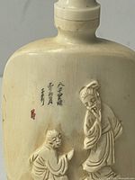 Carved bone snuff bottle showing relief figures and signature