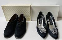 Two pairs of Stuart Weitzman black women’s shoes; left suede lace-up, right pumps with rhinestones, boxes behind
