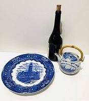 Overview of teapot with lid, commemorative plate and size reference bottle