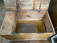Trunk interior showing raw wood, fabric remnants, inner compartment and hinge hardware