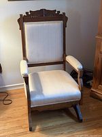 Front view of wooden rocking chair with cream upholstery